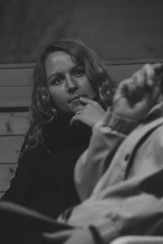 Introspective black and white portrait of a woman sitting and contemplating.